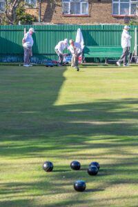 Close-up of bowls gathered around the jack on the grass during a game